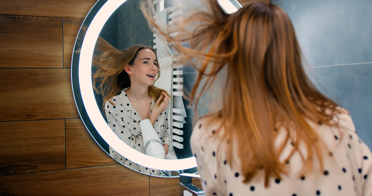 Mujer joven usando espejo vanity con luz para arreglarse el cabello