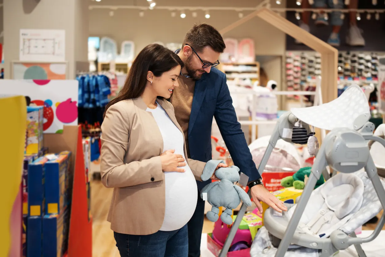 Pareja joven en Store para bebés con una gran cantidad de accesorios y ropa para bebé