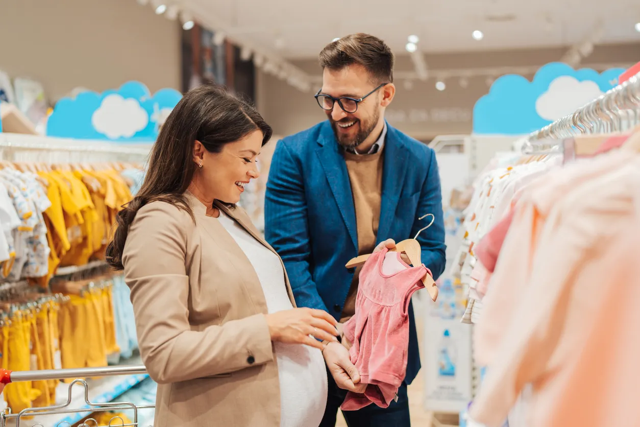 Pareja eligiendo ropa de niña en tienda al mayoreo