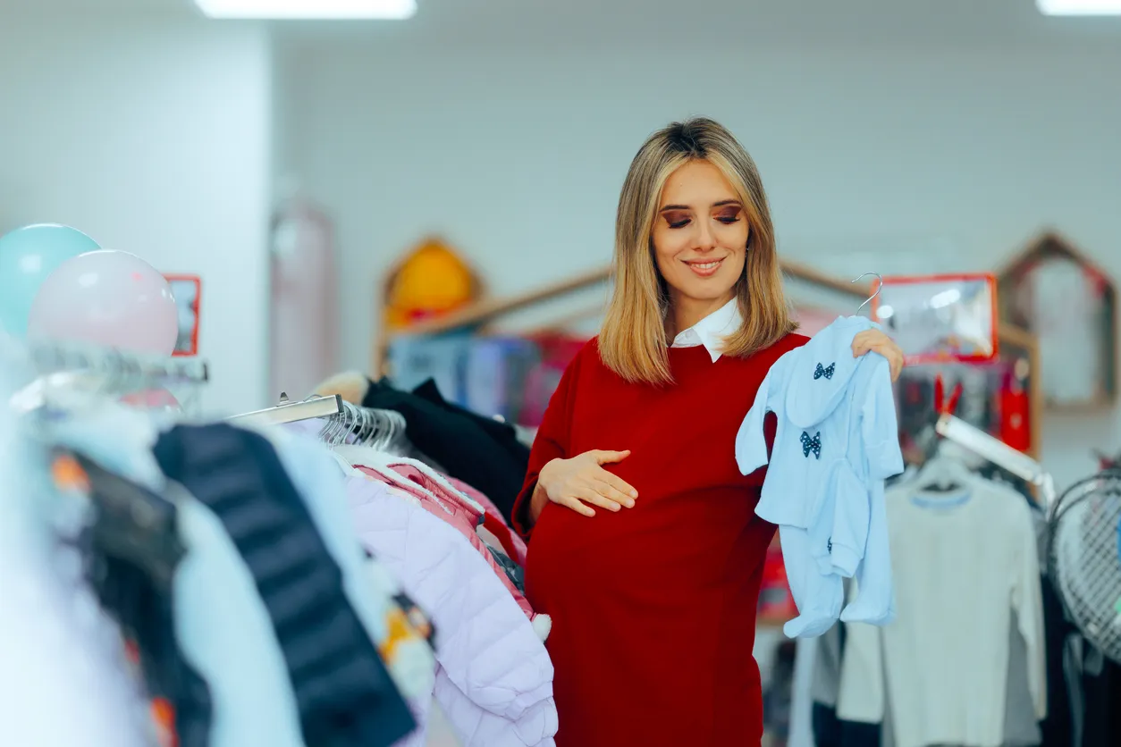 Joven mujer eligiendo mamelucos para su bebe en tienda