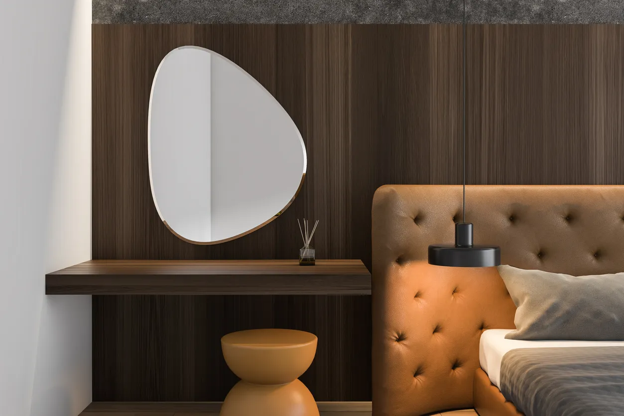 Primer plano de un dormitorio principal de madera con gran espejo de forma irregular