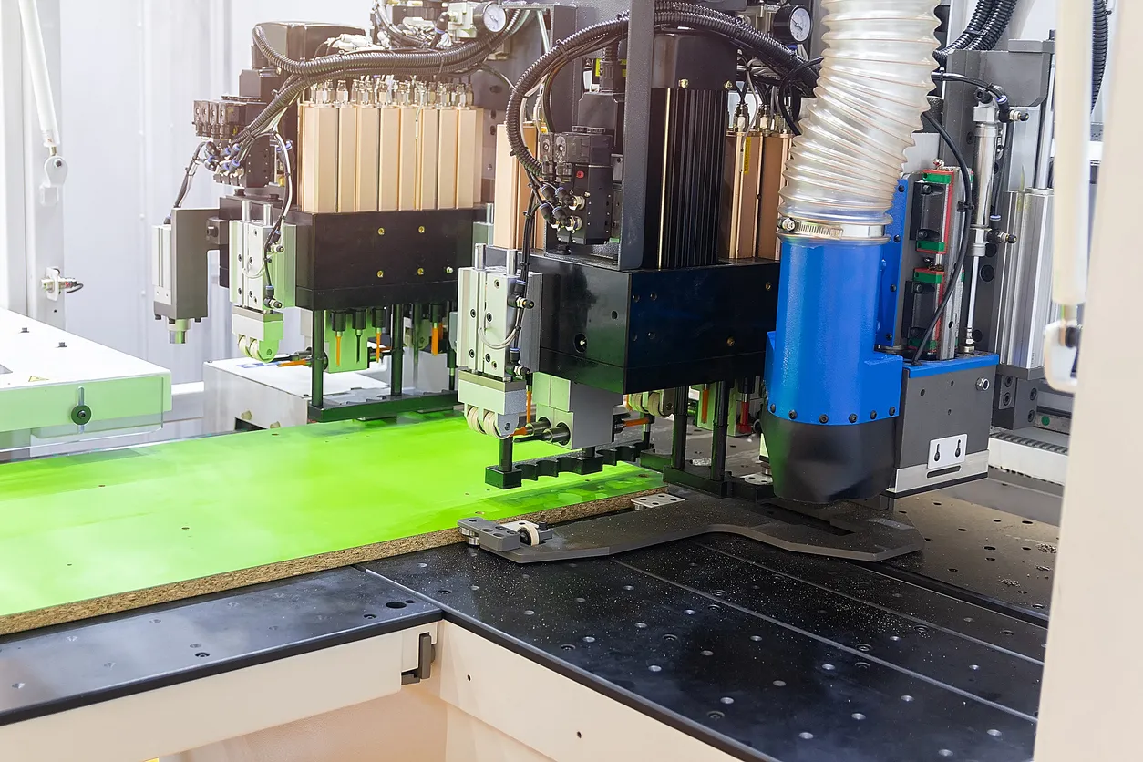 Una moderna máquina automática corta piezas de aglomerado en la producción de muebles