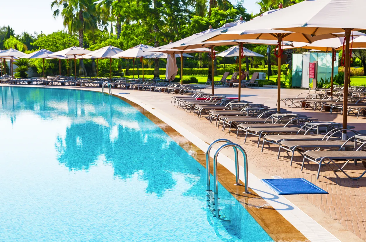 Enorme piscina con palapas alrrededor en un hotel. Con zeolita se logra agua más clara y brillante.