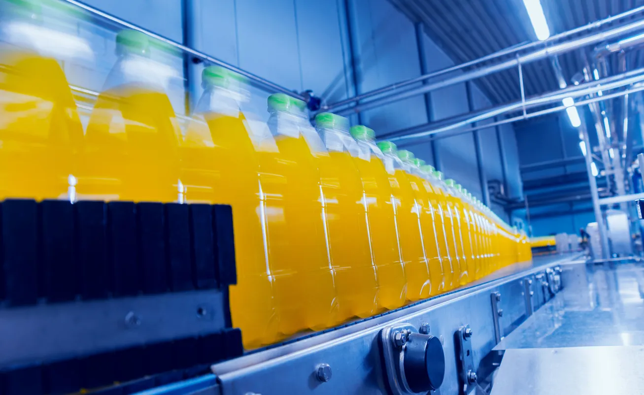 Fábrica de bebidas. Transportador con botellas de jugo.La zeolita ayuda clarificación, pulido y acondicionamiento mineral