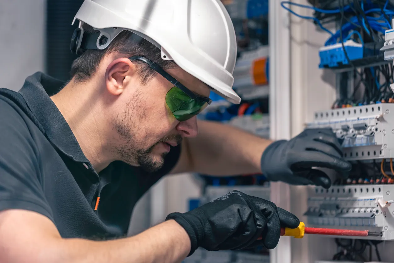 Un electricista trabaja en un cuadro eléctrico utilizando un cable de conexión eléctrica.