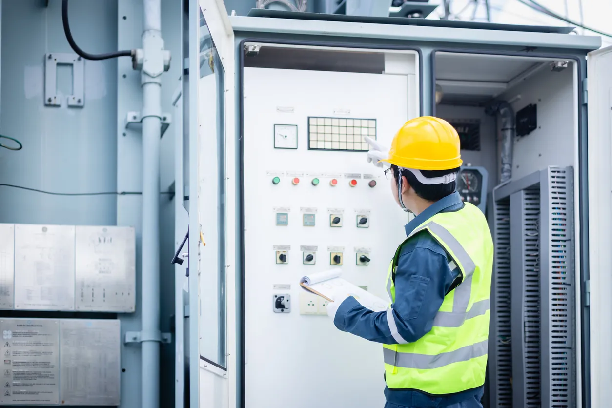 El ingeniero está trabajando en la subestación eléctrica realizando inspecciones de infraestructura de alto voltaje 