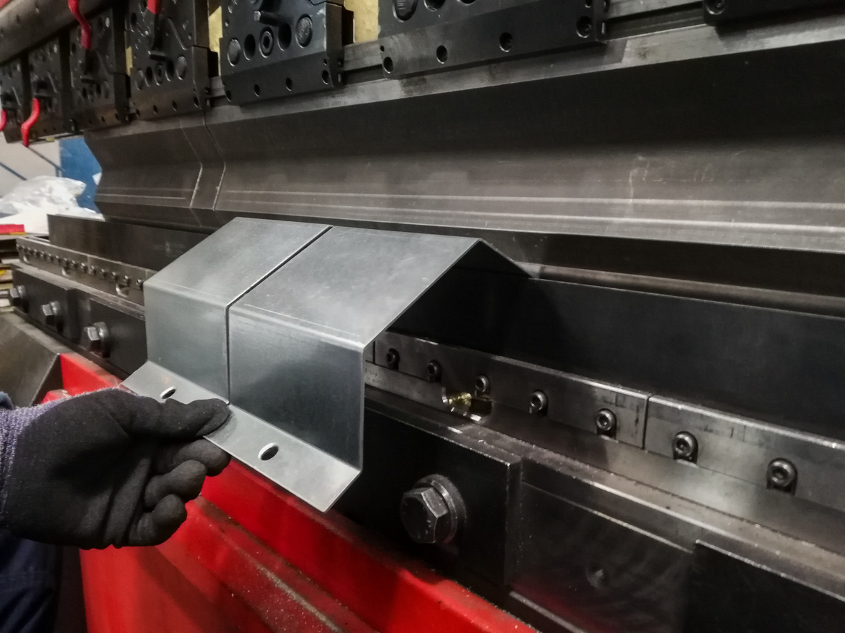 Trabajador metalúrgico que opera la máquina dobladora en una fábrica